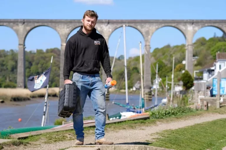 PF & Co Construction team member carrying tools near a viaduct in a scenic riverside location, showcasing professional craftsmanship and dedication.