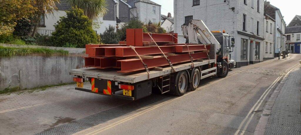 Structural steel delivery by PF & Co Construction Ltd to a constrained site in the South of England, requiring careful coordination with neighbours and temporary works for installation.